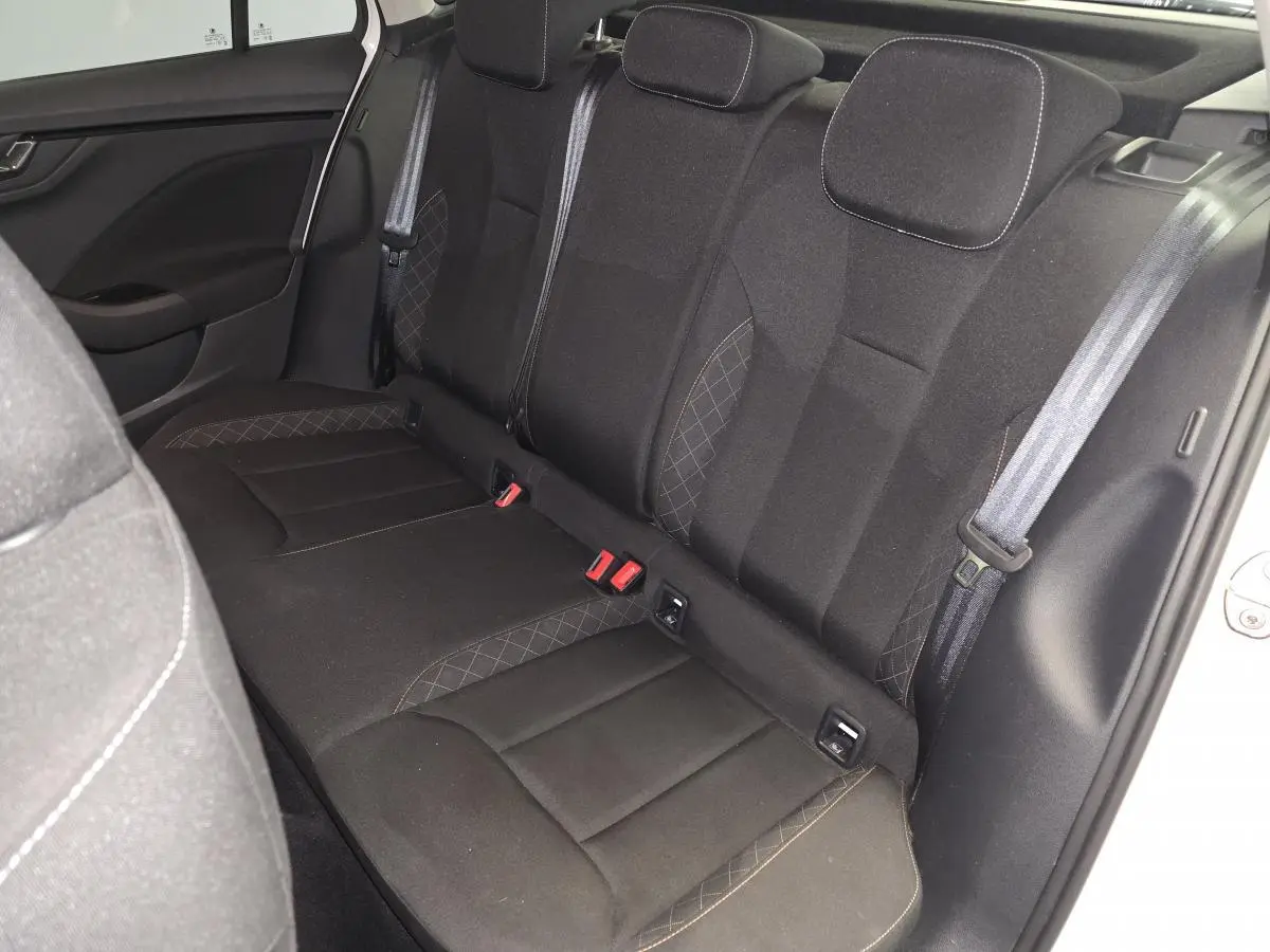 Vue intérieure côté droit de la banquette arrière noire avec appuie-têtes et ceintures visibles du Skoda Kamiq blanc 2023.