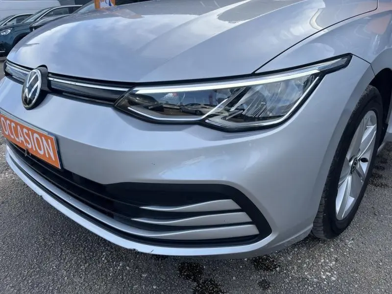 Gros plan sur l'avant droit d'une Volkswagen Golf 1.5 eTSI argent métallisé avec phares LED et calandre noire.