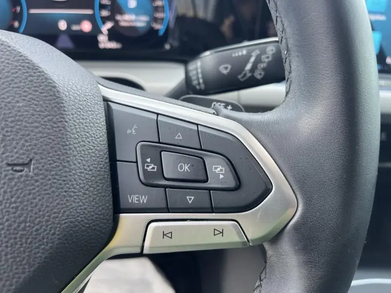 Gros plan sur les commandes multifonctions du volant cuir de la Volkswagen Golf 1.5 eTSI 2020, boutons noirs et argentés.