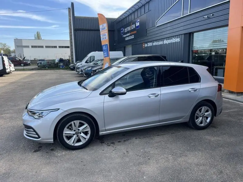 Volkswagen Golf 1.5 eTSI 150ch Life Business en Reflet d'Argent, vue de profil côté gauche sur parking devant concession.