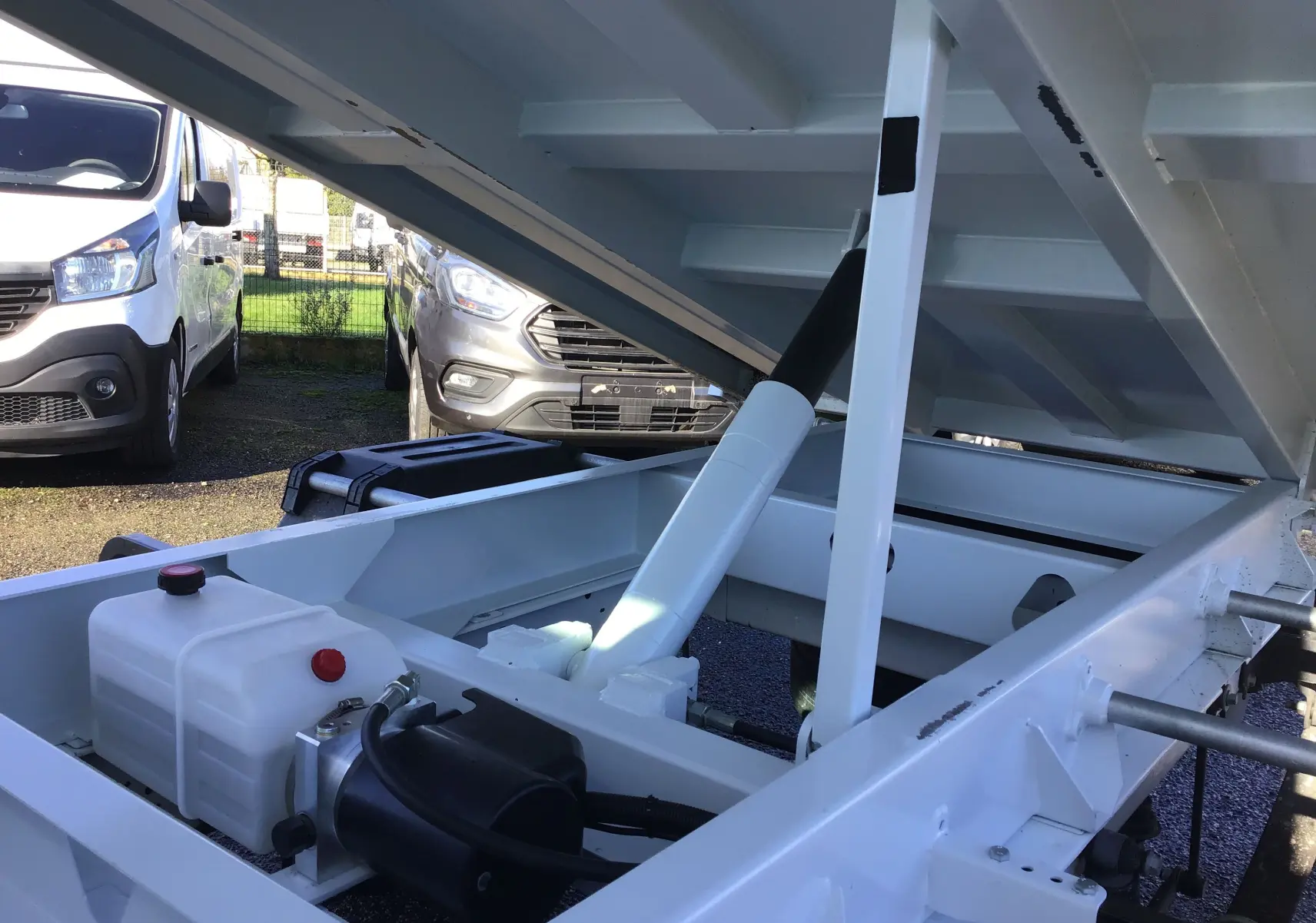 Vue rapprochée du système hydraulique blanc de la benne relevée du Ford Transit Châssis Cabine blanc, côté arrière.