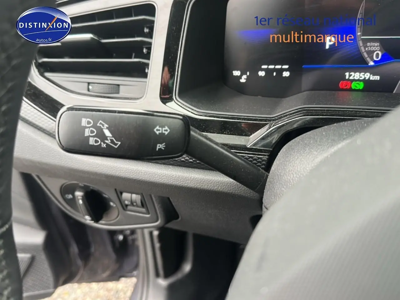 Gros plan sur le commodo gauche et le tableau de bord numérique d'une Volkswagen Polo gris cendre, intérieur noir.