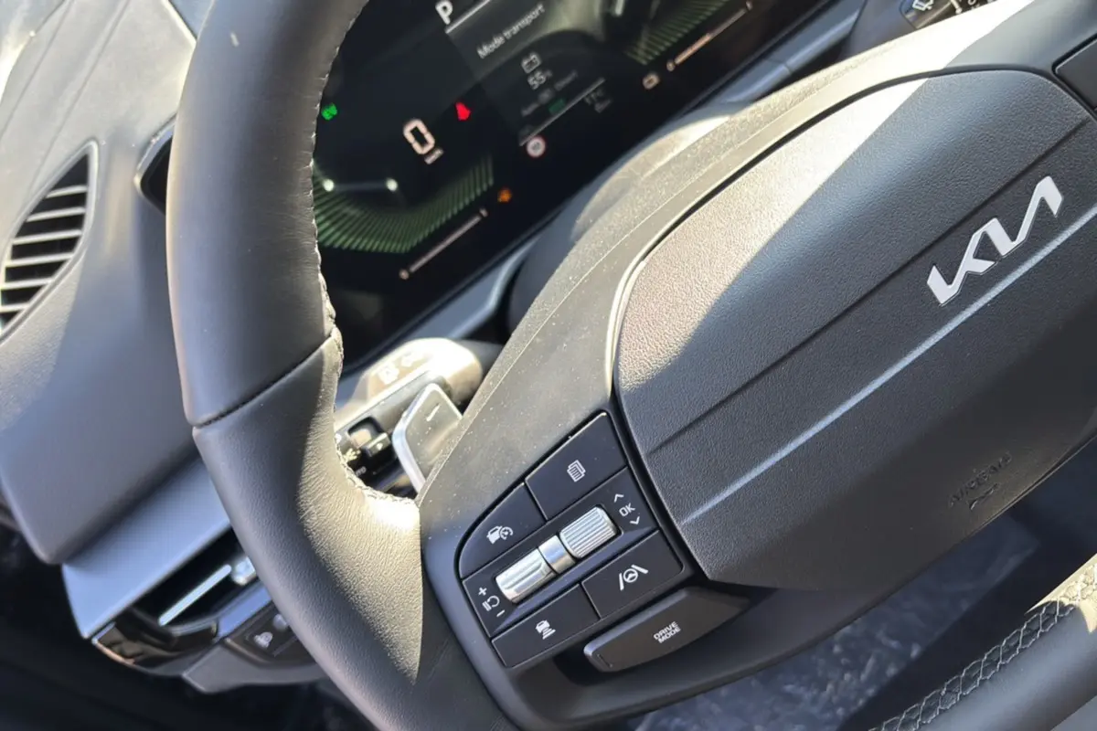 Gros plan sur le volant cuir multifonctions du Kia Sportage 2026, avec commandes intégrées et tableau de bord numérique visible.