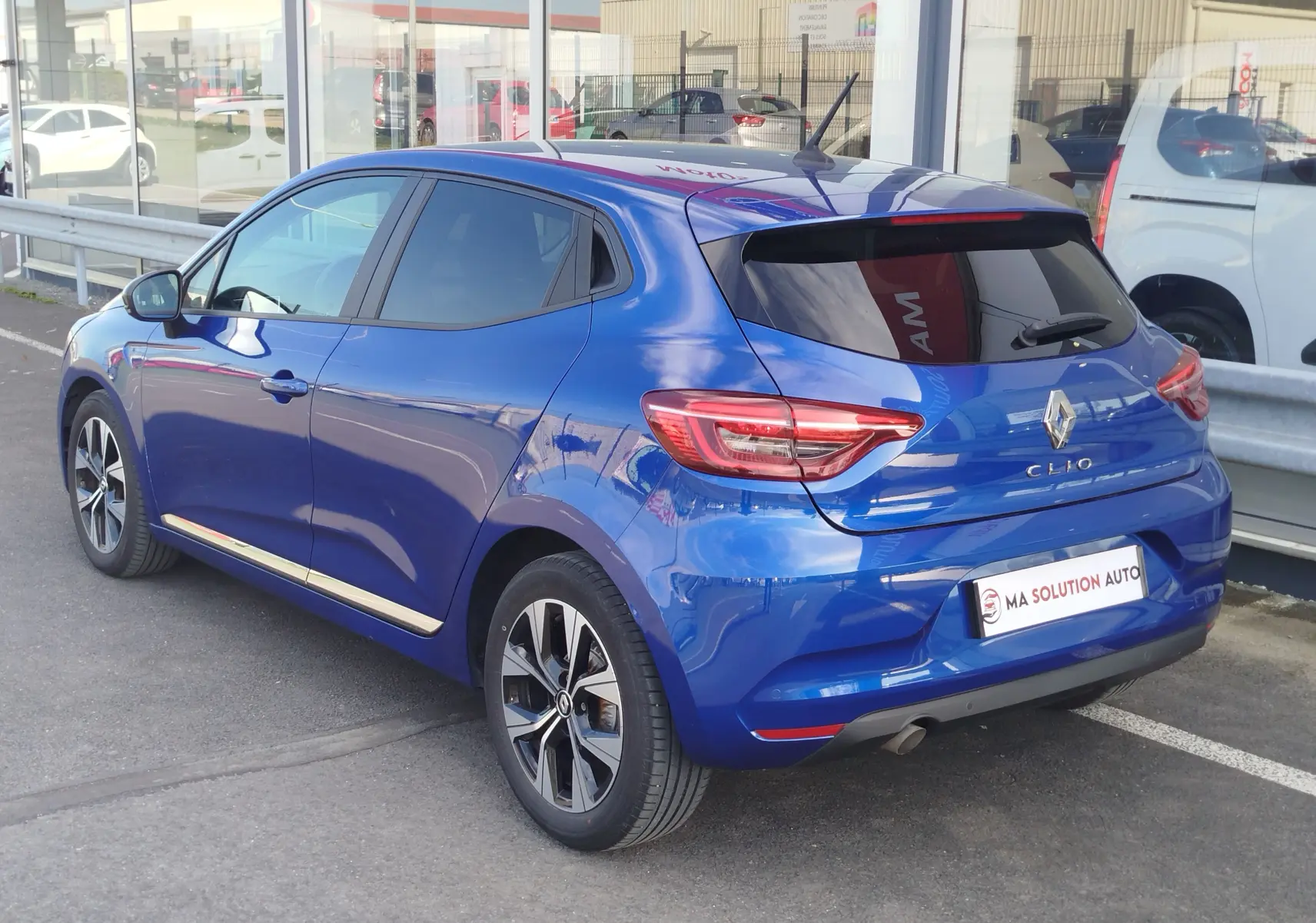 Renault Clio 1.0 SCe 65ch Evolution bleu Iron vue 3/4 arrière droit, jantes alliage et vitres teintées.