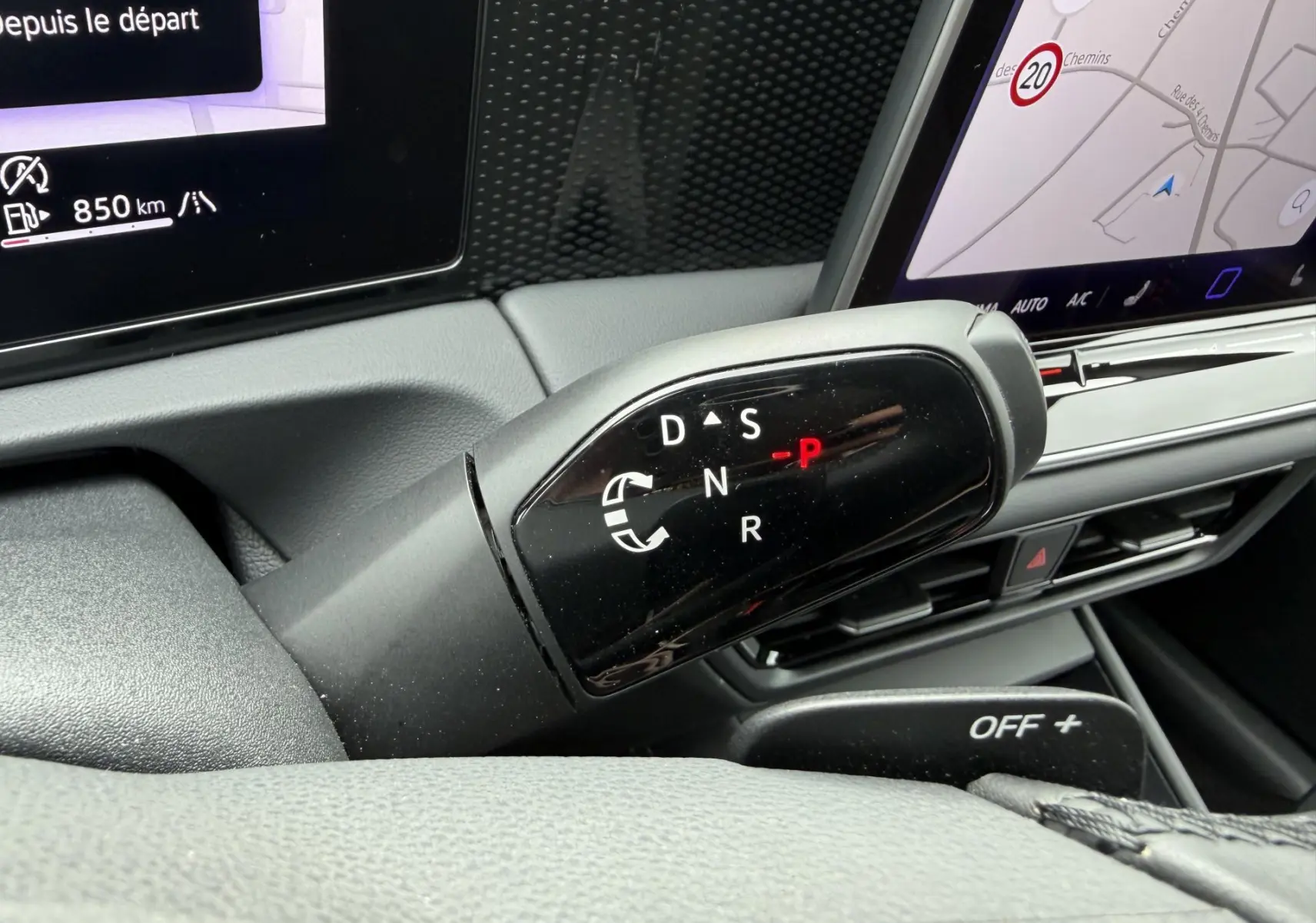Gros plan sur le levier de vitesses noir du Volkswagen Tiguan blanc, avec écran tactile et tableau de bord numériques visibles.