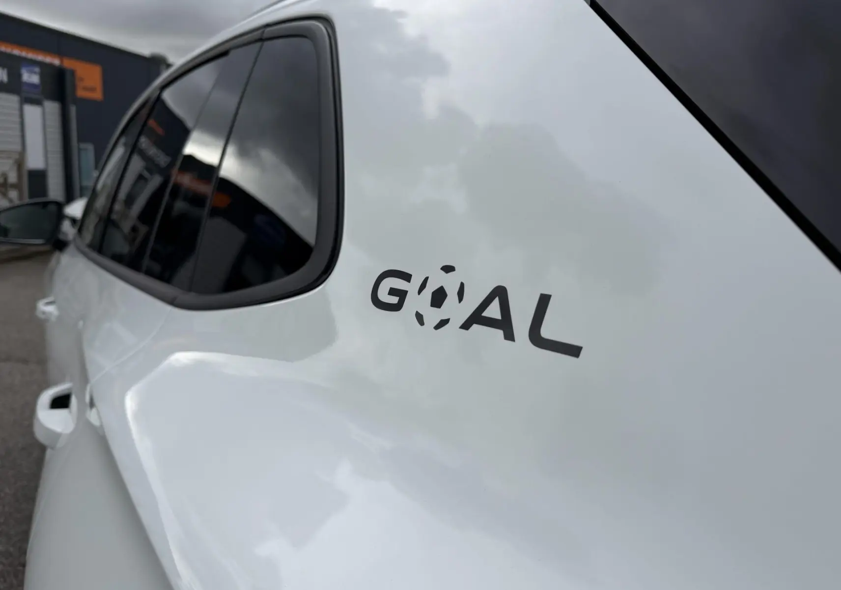 Vue rapprochée du côté gauche arrière du Volkswagen Tiguan blanc 2025 avec logo "GOAL" sur la carrosserie.
