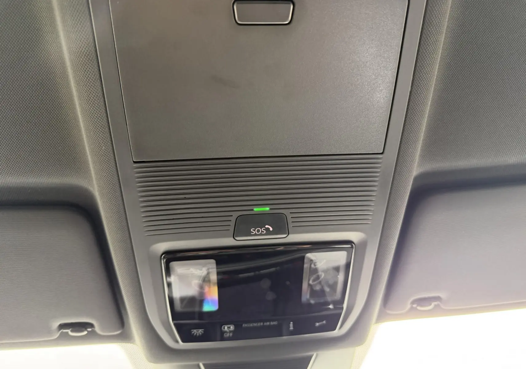 Vue intérieure du plafonnier gris du Volkswagen Tiguan 2025 avec bouton SOS et éclairage intégré.