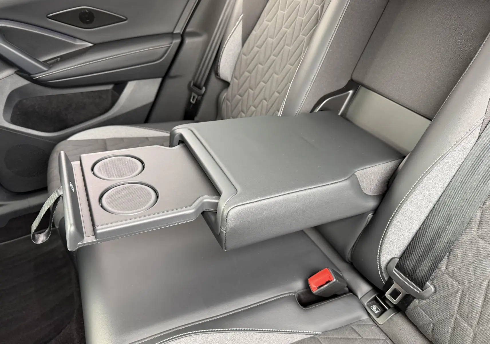 Détail de l'accoudoir central arrière ouvert avec porte-gobelets dans l'habitacle gris du Volkswagen Tiguan 2025.