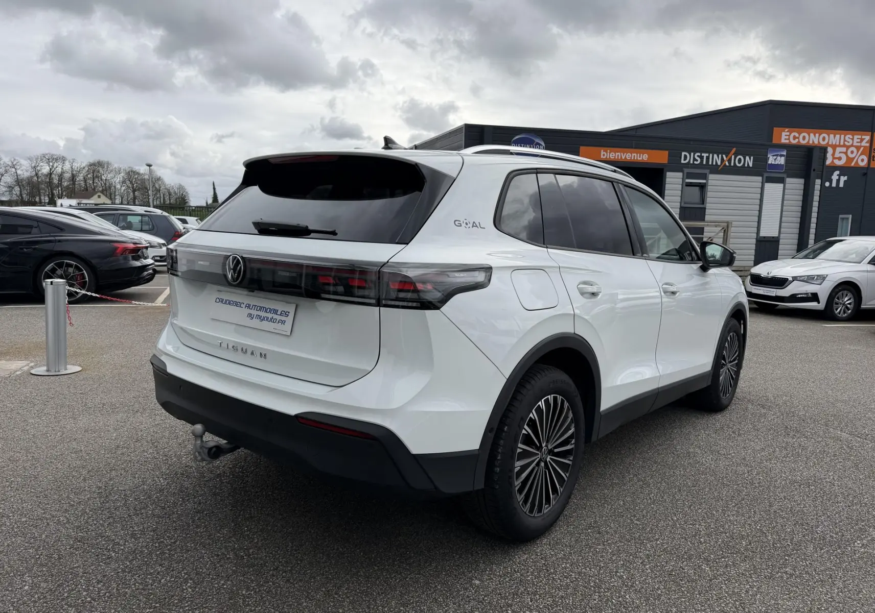 Vue 3/4 arrière droite du Volkswagen Tiguan blanc avec vitres arrière teintées et attelage rabattable visible.