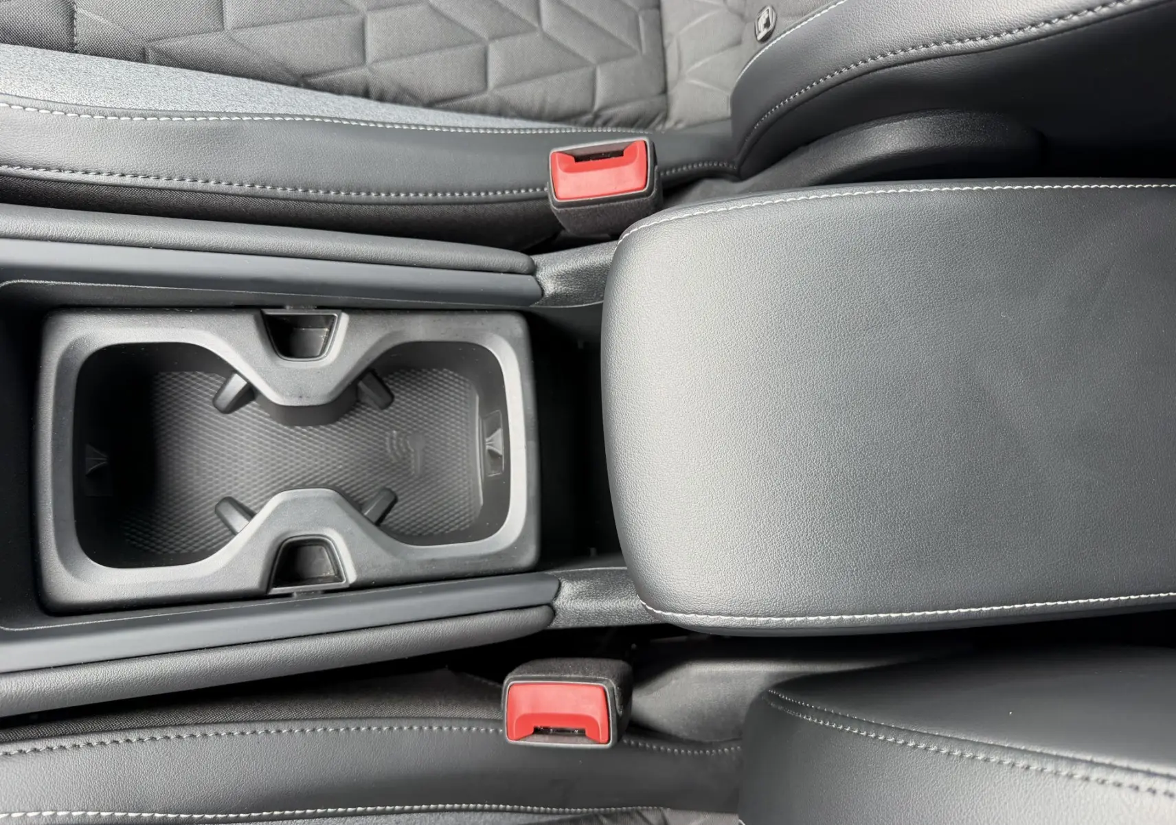 Vue rapprochée de la console centrale noire avec porte-gobelets et accoudoir en cuir du Volkswagen Tiguan 2025.