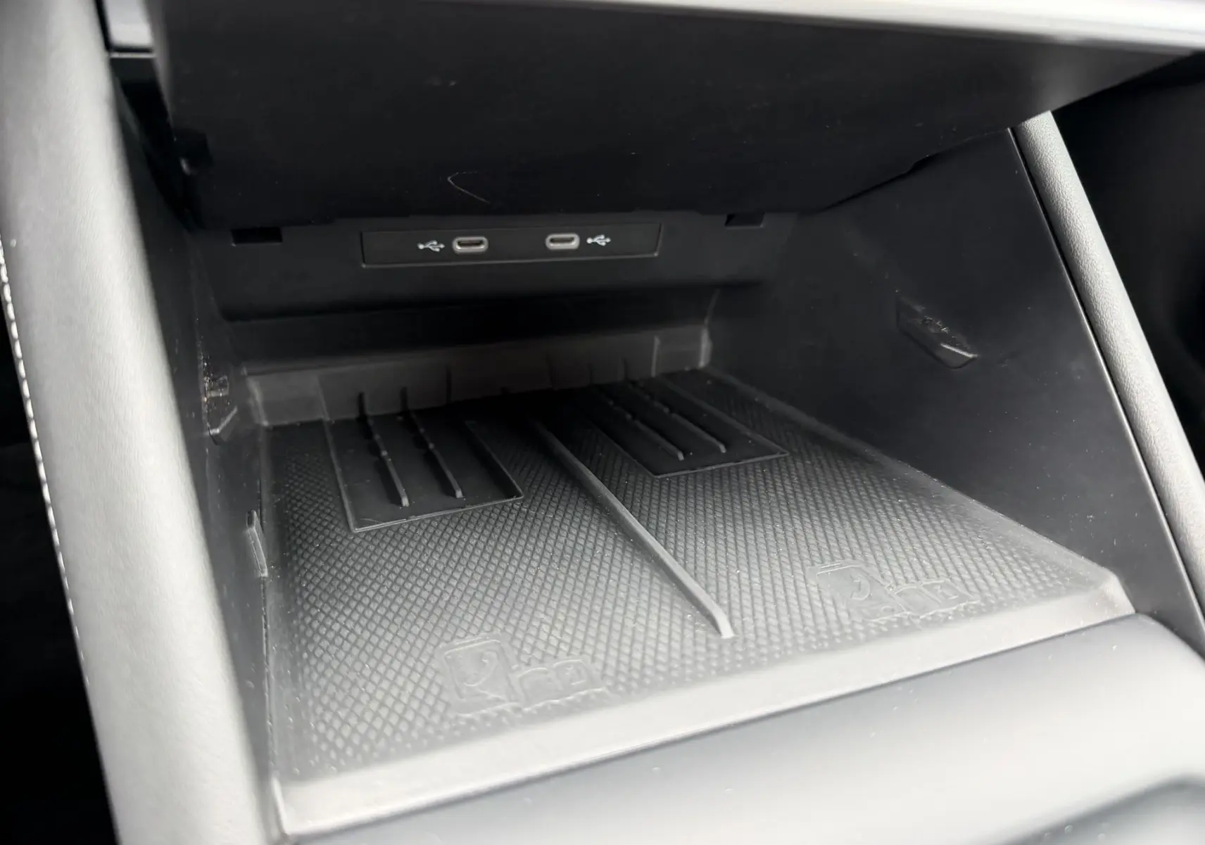 Gros plan sur le compartiment de recharge sans fil noir avec ports USB-C du Volkswagen Tiguan 2025, intérieur sobre.