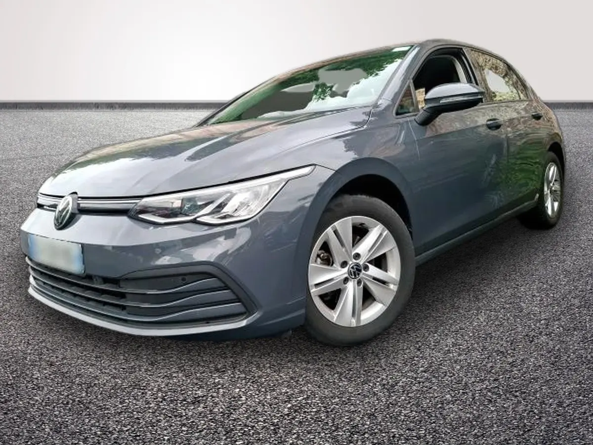 Volkswagen Golf gris clair vue 3/4 avant droit, avec jantes alliage et phares LED allumés.