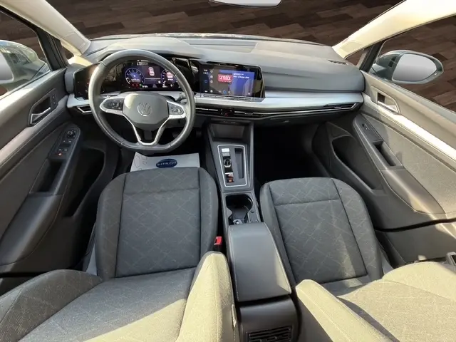 Vue intérieure avant de la Volkswagen Golf 2023 gris clair, avec tableau de bord numérique et écran tactile central.