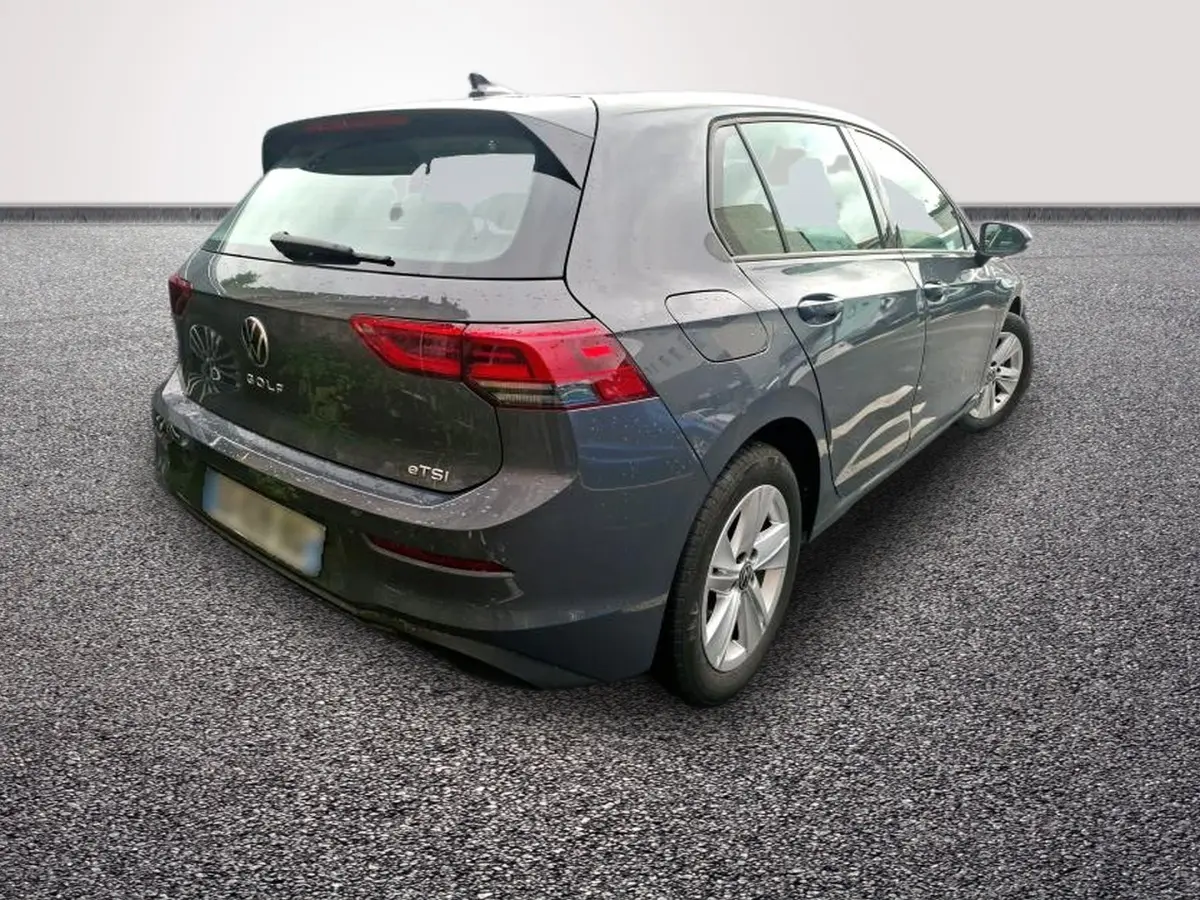 Volkswagen Golf gris clair vue 3/4 arrière droit, avec feux LED et logo VW visible sur le hayon.