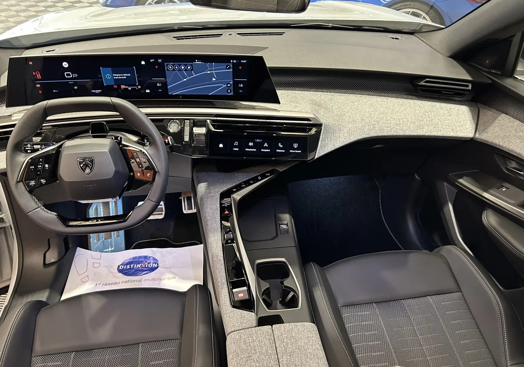 Vue intérieure avant du Peugeot 3008 Hybrid blanc Okenite, avec tableau de bord numérique panoramique et sellerie noire.