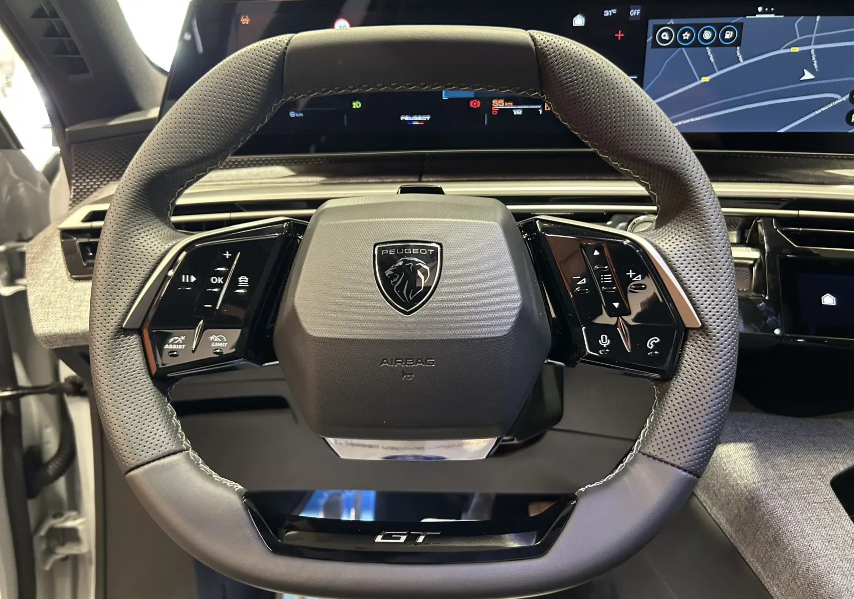 Vue rapprochée du volant cuir perforé noir du Peugeot 3008 III Hybrid GT avec logo lion et commandes intégrées.