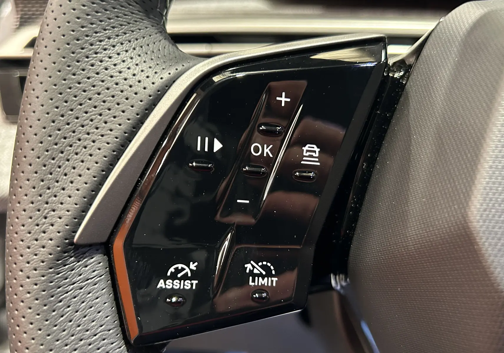 Gros plan sur les commandes noires du volant côté gauche du Peugeot 3008 Hybrid blanc Okenite.