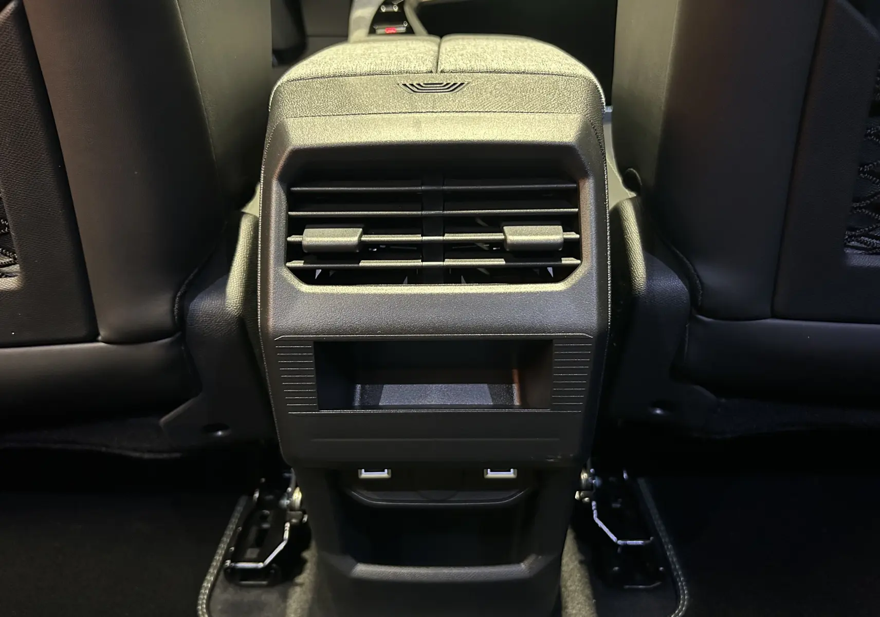 Vue rapprochée de la console arrière noire avec bouches d’aération et ports USB du Peugeot 3008 Hybrid blanc.