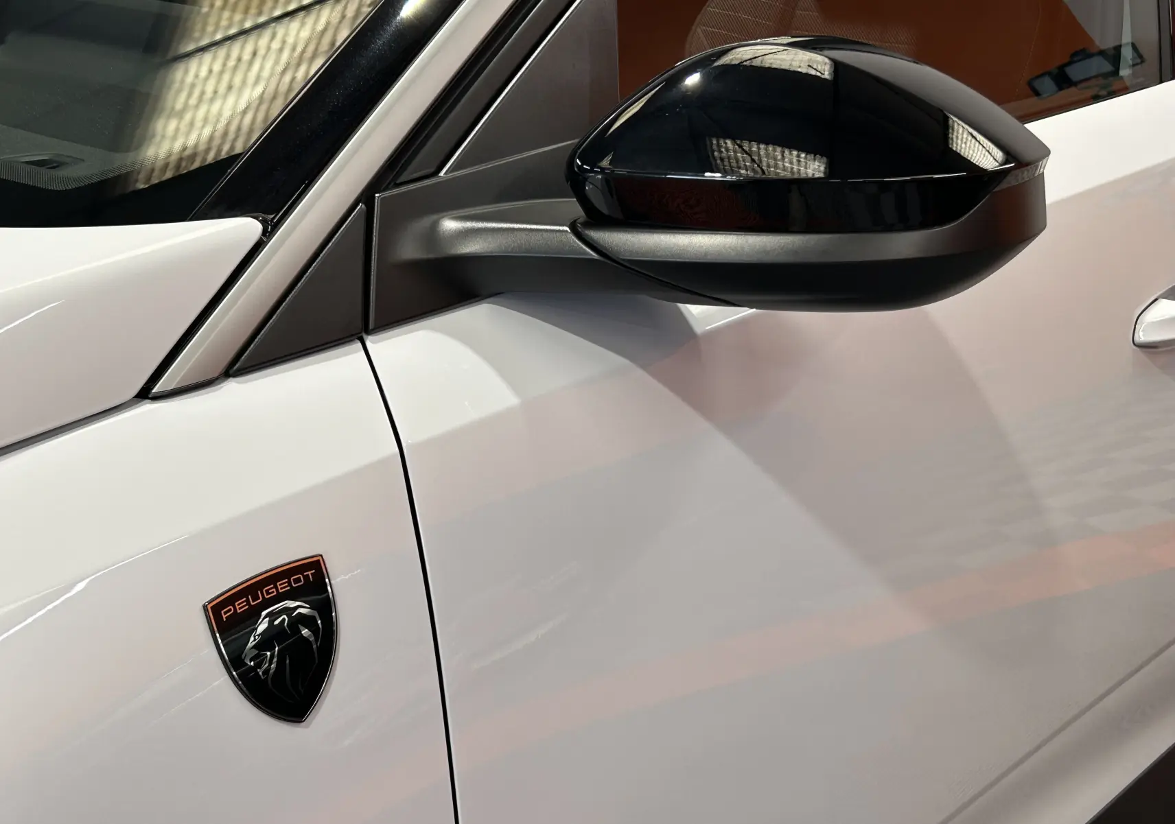 Détail du côté gauche blanc Okenite du Peugeot 3008 Hybrid avec rétroviseur noir brillant et logo Peugeot noir et cuivre.