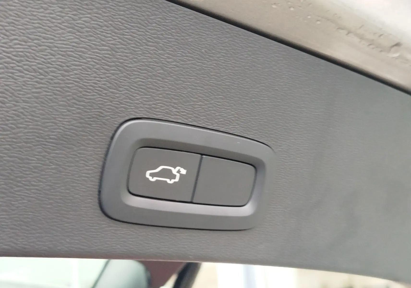 Bouton d'ouverture électrique du coffre sur la garniture intérieure beige du Volvo XC40 D3 2020.