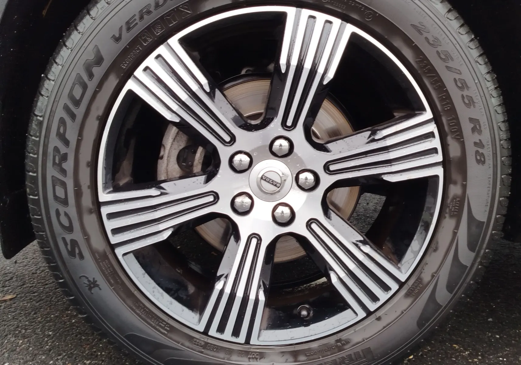 Gros plan sur la jante alliage bicolore noire et argentée d’un Volvo XC40 beige, avec pneu Pirelli Scorpion Verde.