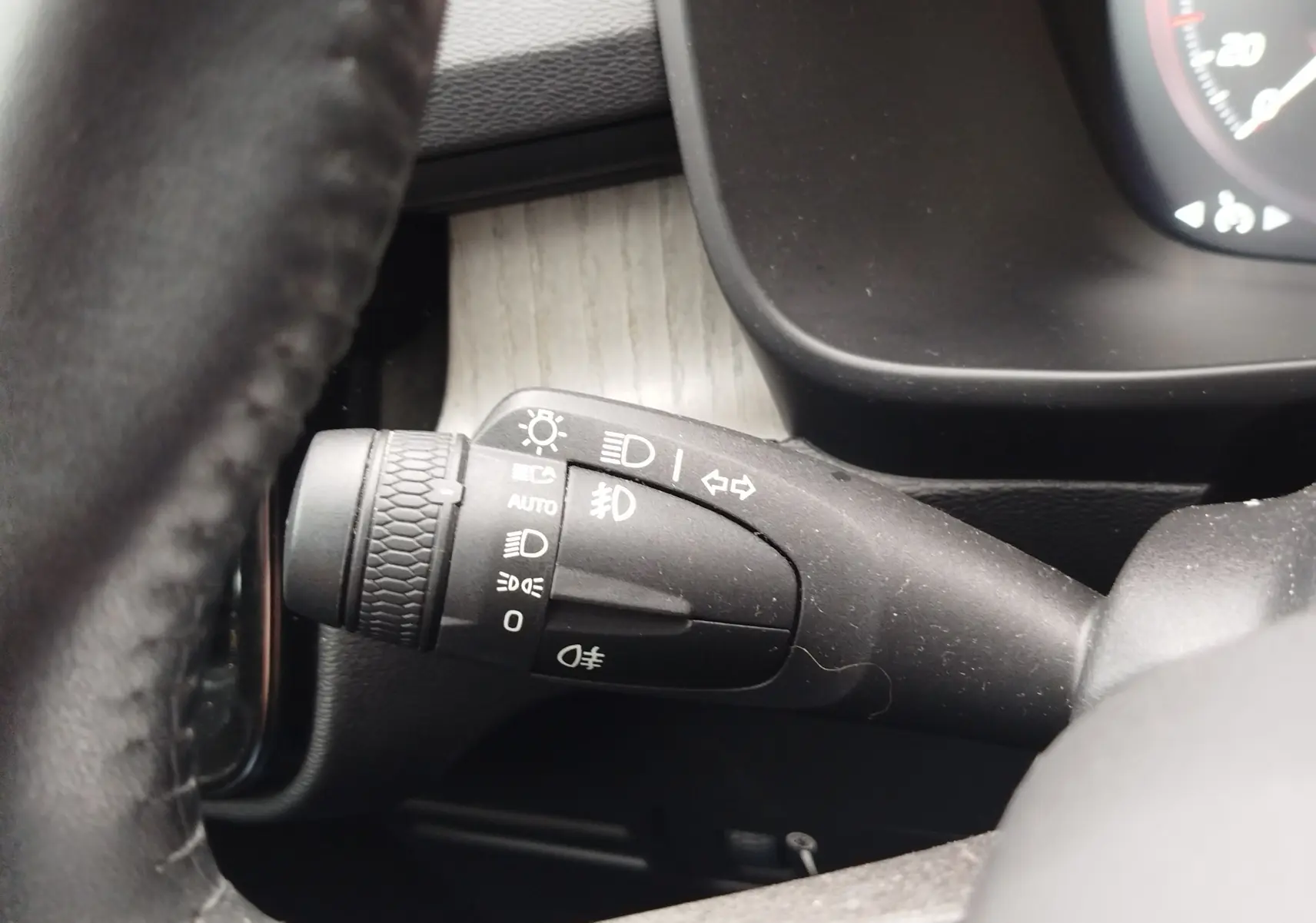 Gros plan sur la manette de commande des phares à gauche du volant dans l’habitacle beige du Volvo XC40 D3 2020.