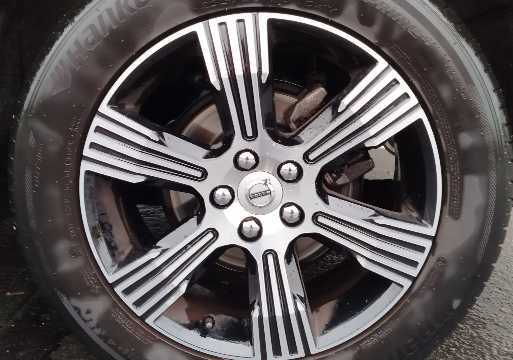 Gros plan sur la jante alliage bicolore noire et argentée du Volvo XC40 beige, mettant en valeur le logo central Volvo.