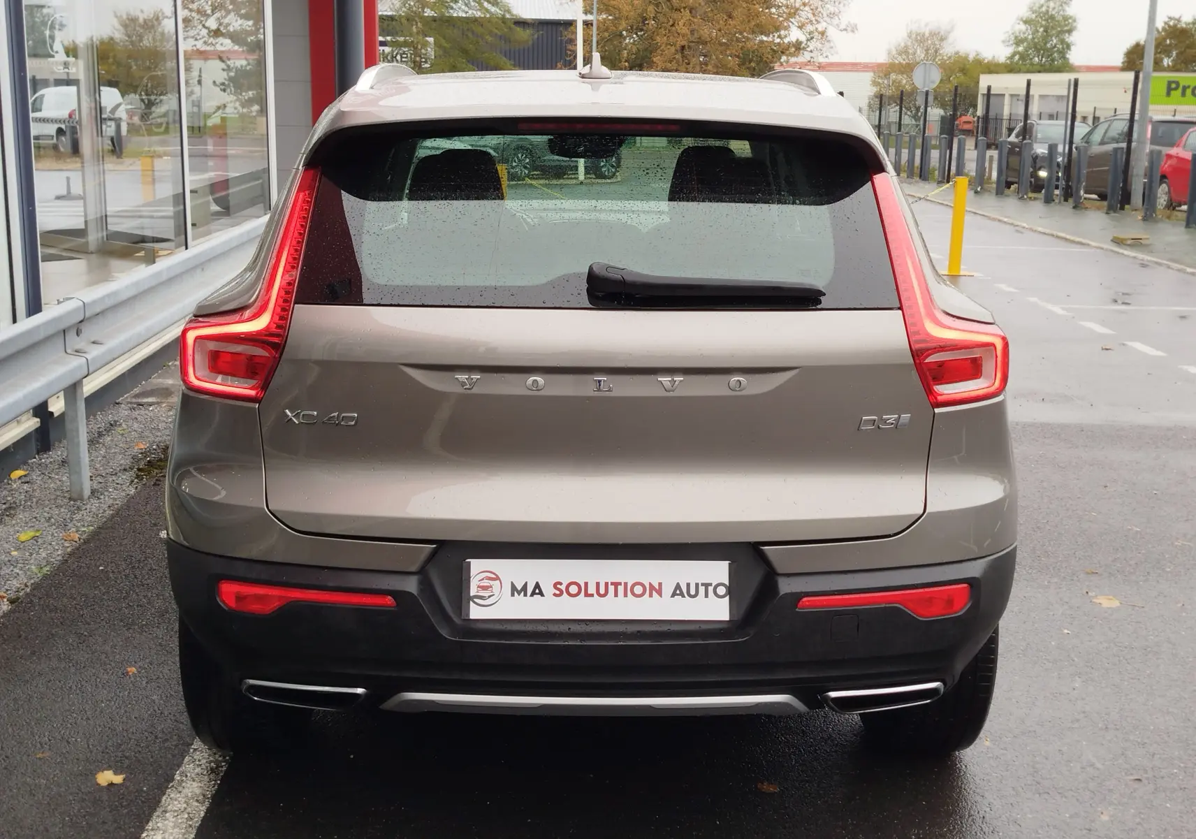 Vue arrière d'un Volvo XC40 beige 2020 avec feux LED caractéristiques et double sortie d'échappement chromée.