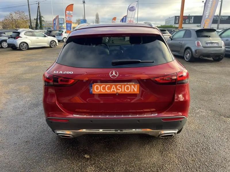 Vue arrière d'une Mercedes GLA 200 rouge Patagonie métallisé avec plaque "OCCASION" sur parking extérieur.