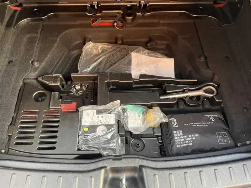 Coffre ouvert d'une Mercedes GLA 200 Business Line 2021, montrant le rangement d'outils et kit de secours intégré.