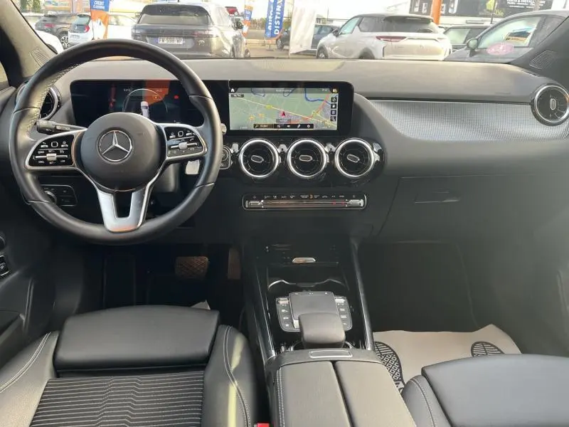 Vue intérieure avant du tableau de bord et volant cuir noir d'une Mercedes GLA 200 Business Line 2021 avec écran tactile et navigation.
