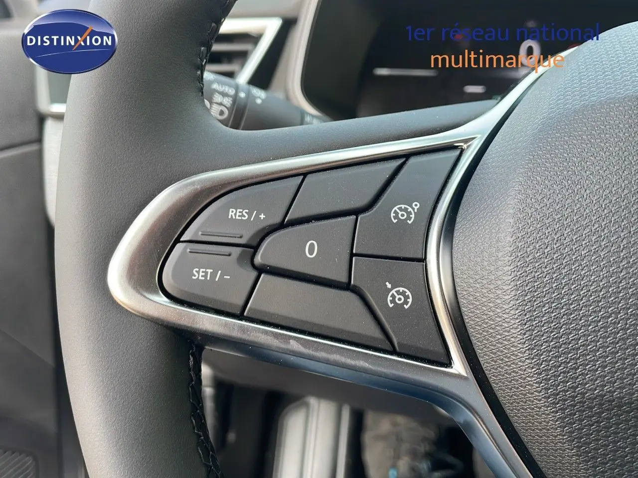Gros plan sur les commandes de régulateur de vitesse au volant d'une Renault Clio gris schiste métal, intérieur moderne.