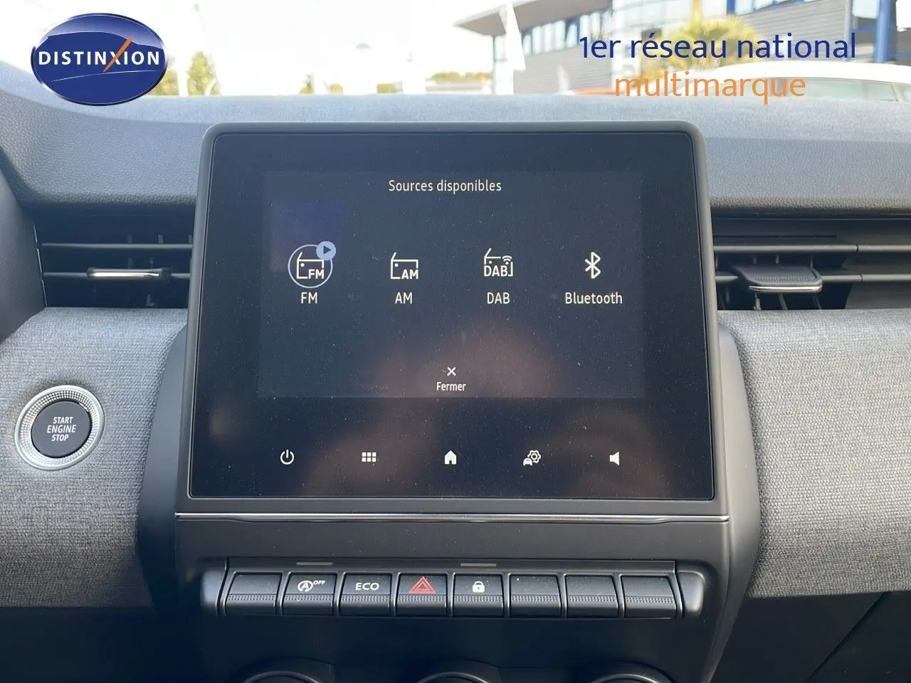 Vue intérieure centrée sur l'écran tactile multimédia de la Renault Clio gris schiste 2025, avec bouton start visible.