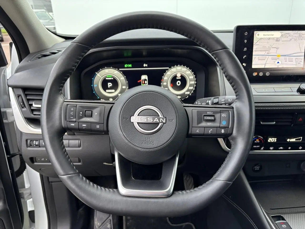 Vue centrée sur le volant cuir noir du Nissan Qashqai III 2025 avec tableau de bord numérique et écran tactile GPS.