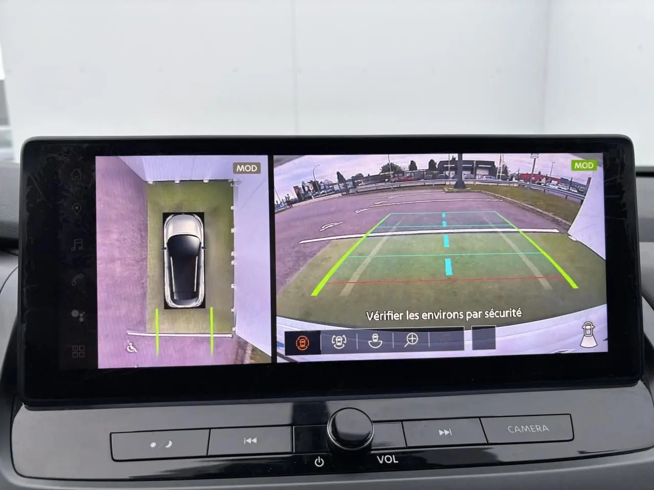 Écran multimédia affichant la caméra 360° du Nissan Qashqai blanc nacré, vue de dessus et arrière en stationnement.