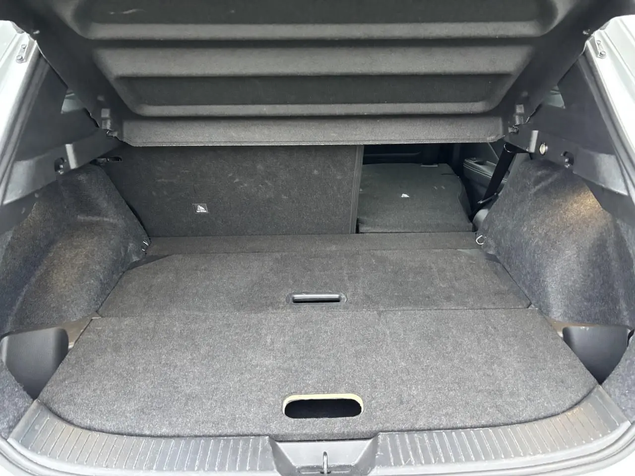 Coffre ouvert du Nissan Qashqai blanc nacré 2025 avec banquette arrière rabattue et plancher plat.