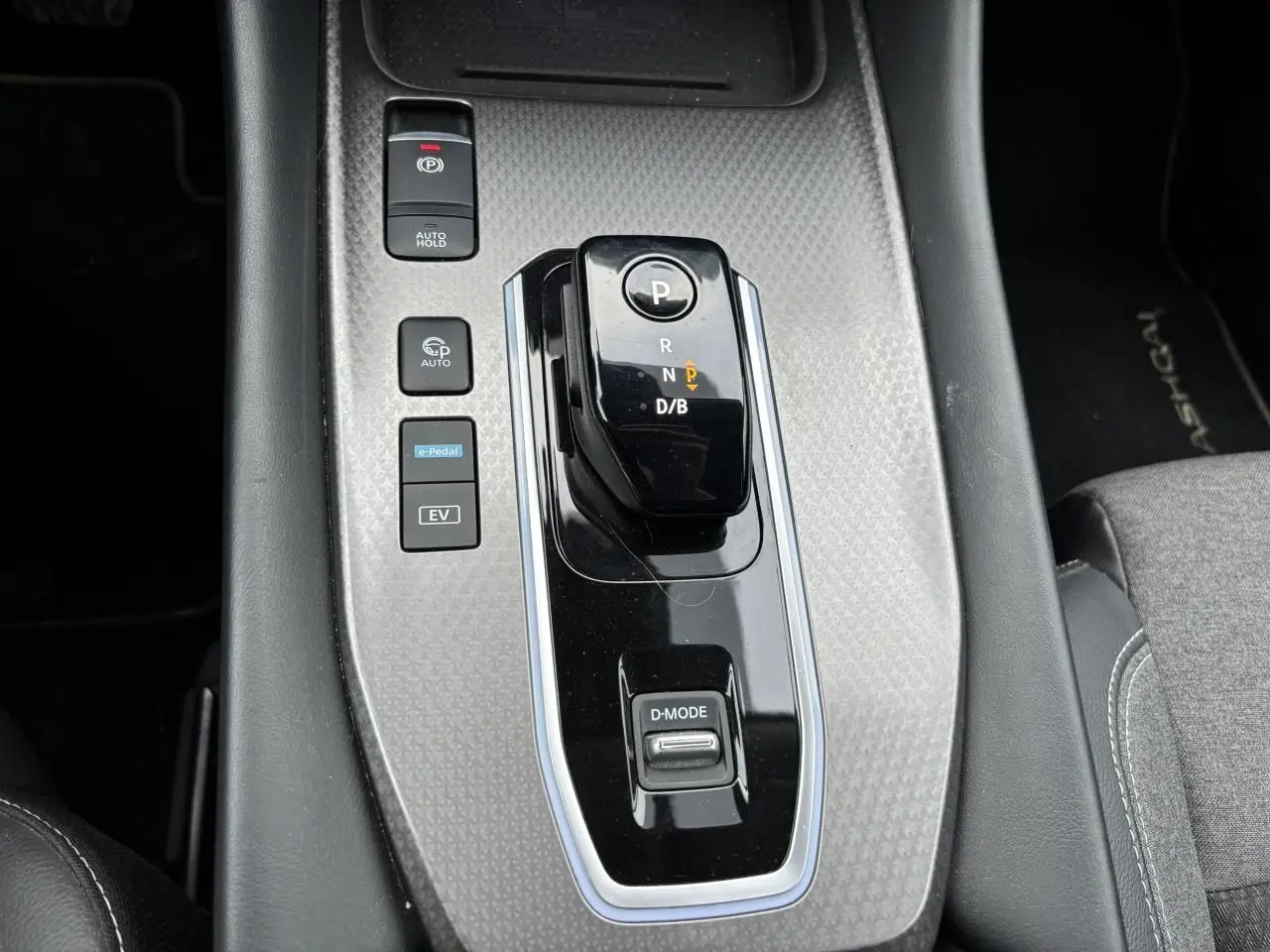 Gros plan sur la console centrale du Nissan Qashqai blanc nacré, avec levier de vitesses automatique et boutons e-Pedal et EV.