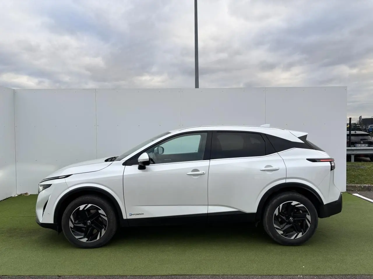 Vue de profil côté gauche du Nissan Qashqai III blanc nacré avec jantes alliage noires et toit contrasté noir.