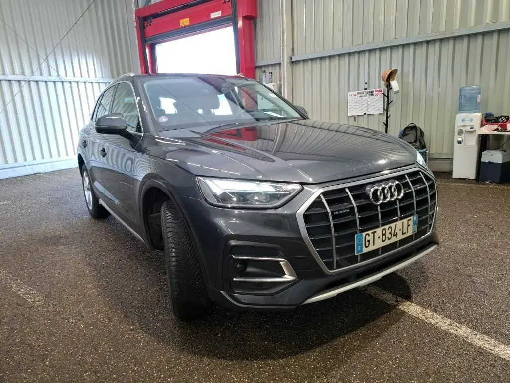 Audi Q5 gris en 3/4 avant droit, avec calandre large et jantes en alliage à 5 branches doubles.