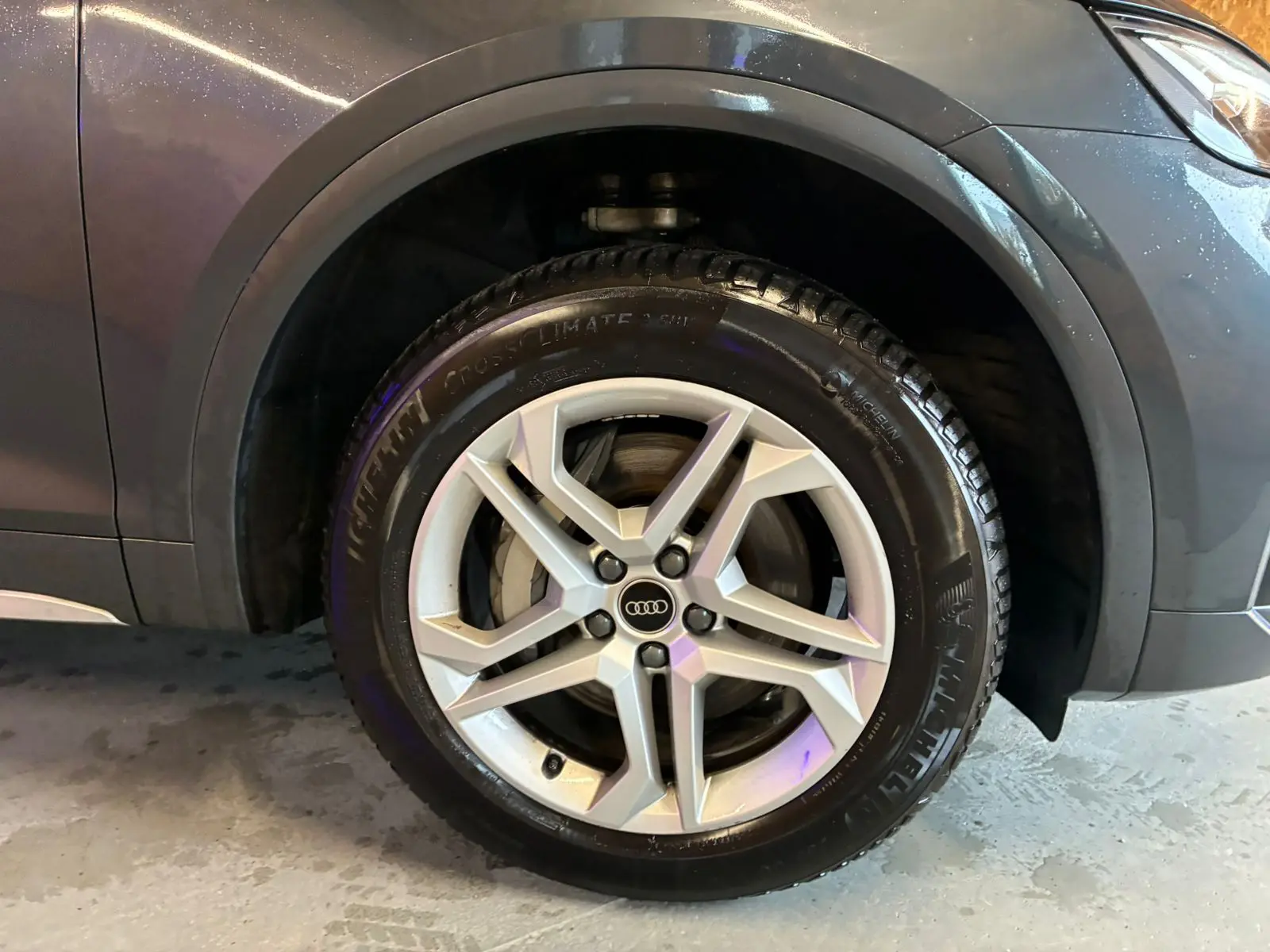 Gros plan sur la roue avant gauche gris argent avec jante aluminium 5 branches doubles d’un Audi Q5 hybride rechargeable 2024.