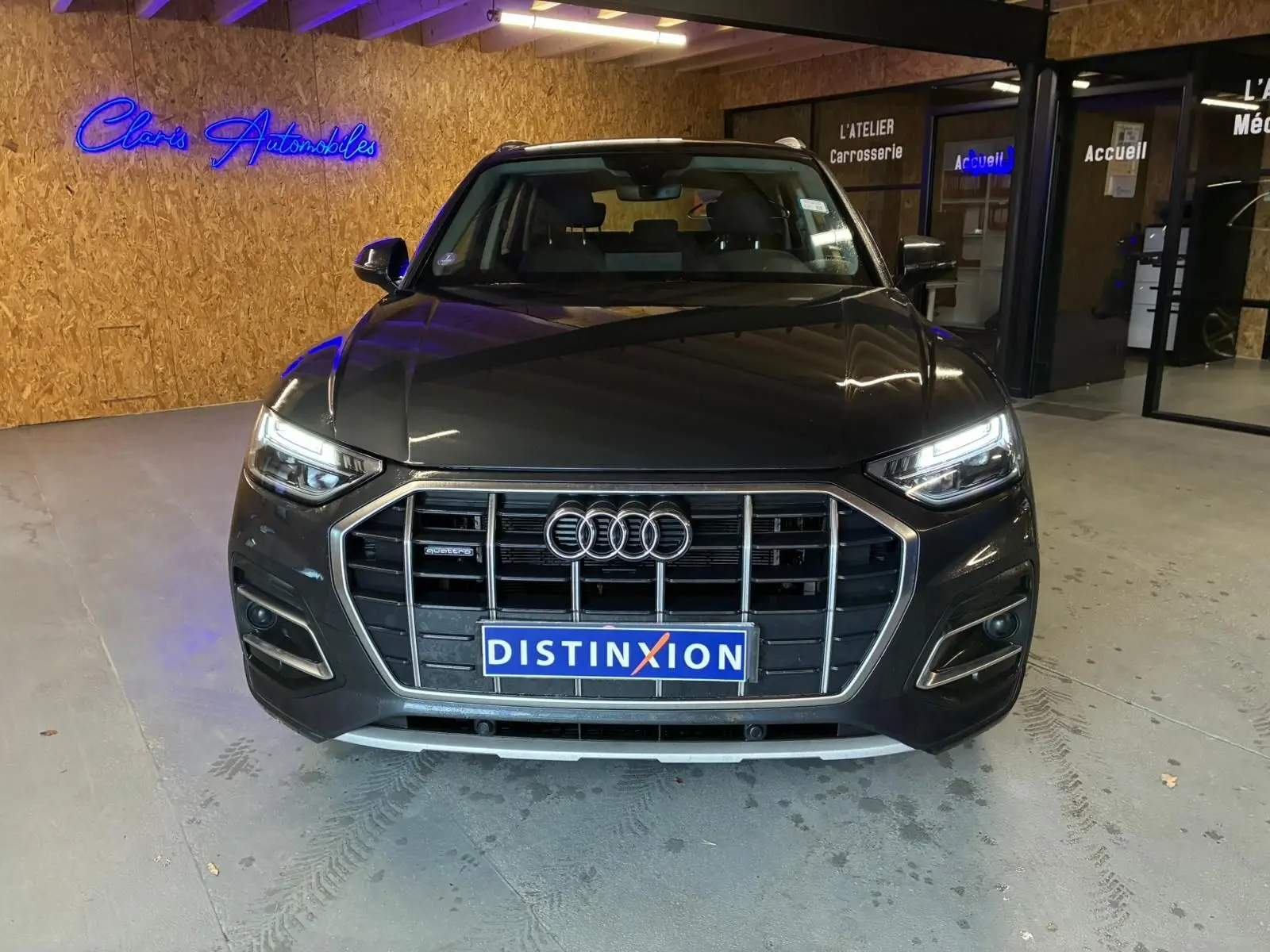 Vue frontale d'un Audi Q5 gris avec calandre imposante et phares LED allumés dans un garage.