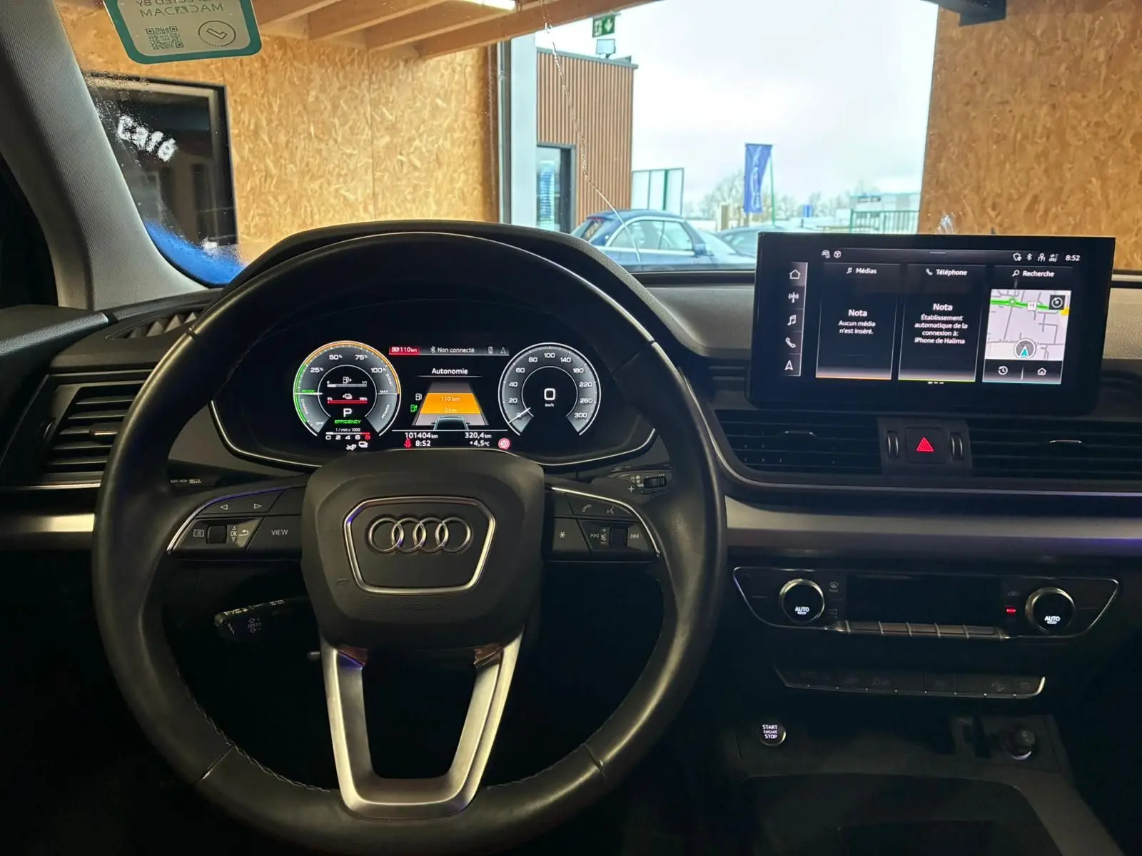 Vue intérieure centrée sur le volant Audi et le tableau de bord numérique du Q5 hybride rechargeable gris 2024.