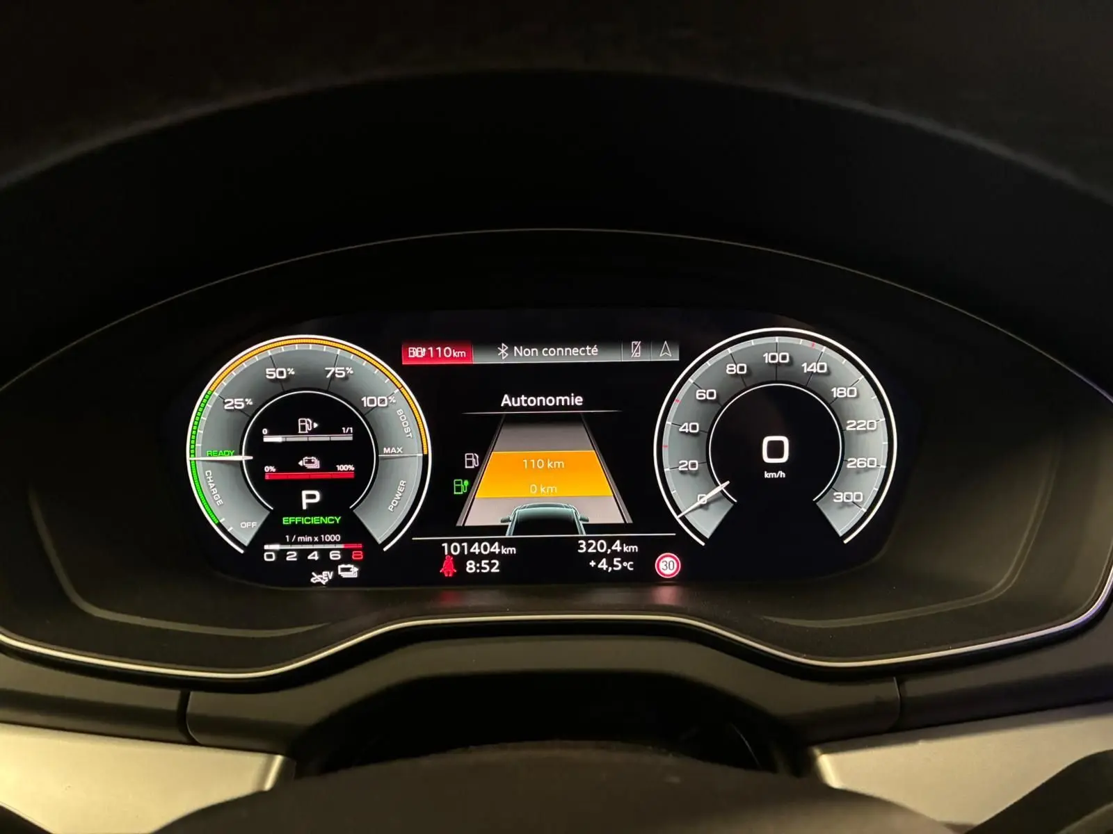 Vue rapprochée du tableau de bord numérique de l'Audi Q5 gris, affichant l'autonomie et la vitesse à 0 km/h.