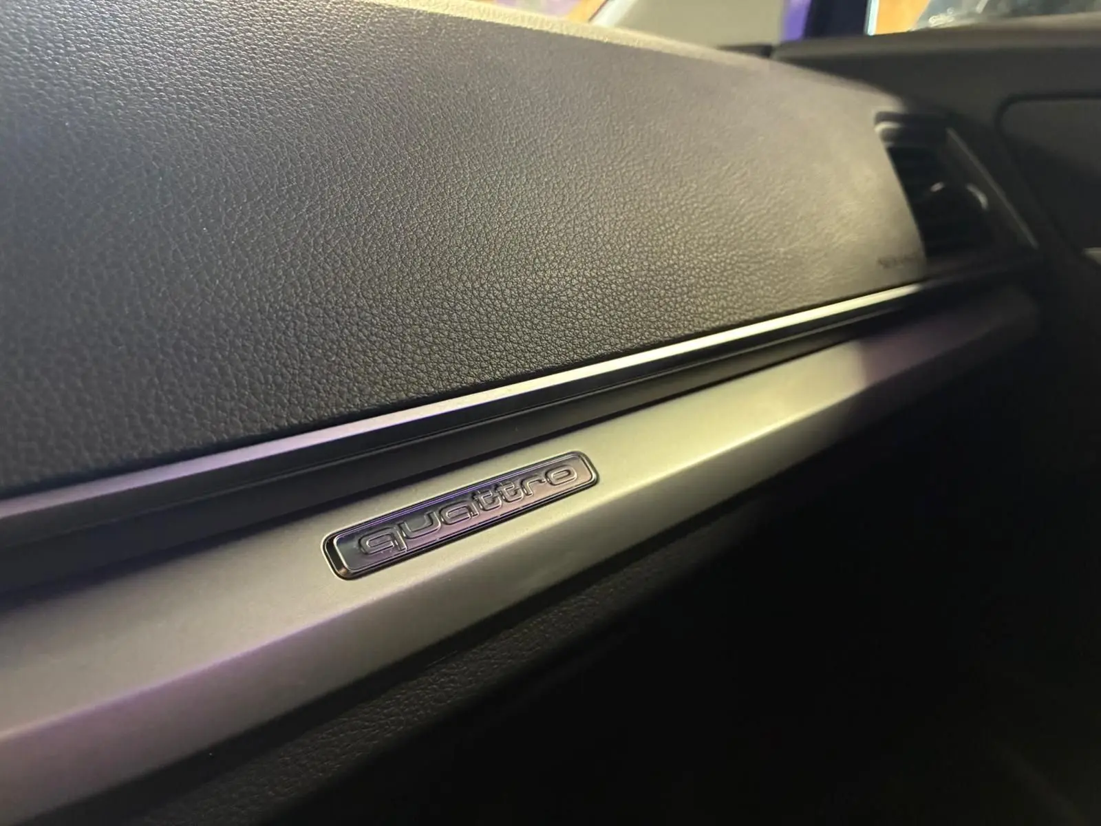 Détail intérieur du tableau de bord avec insert aluminium et logo quattro sur Audi Q5 gris 2024.