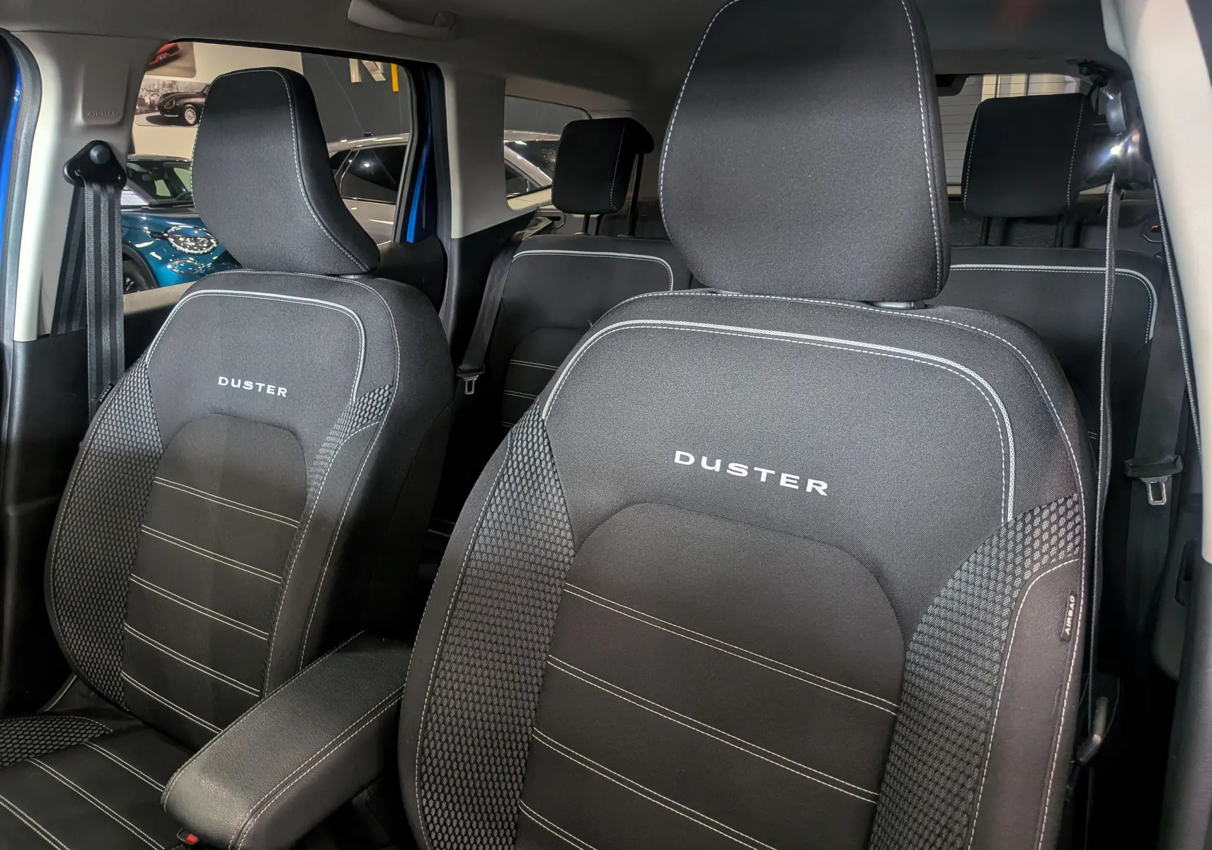 Gros plan sur les sièges avant noirs en tissu du Dacia Duster 2022 avec logo DUSTER brodé, intérieur visible en arrière-plan.
