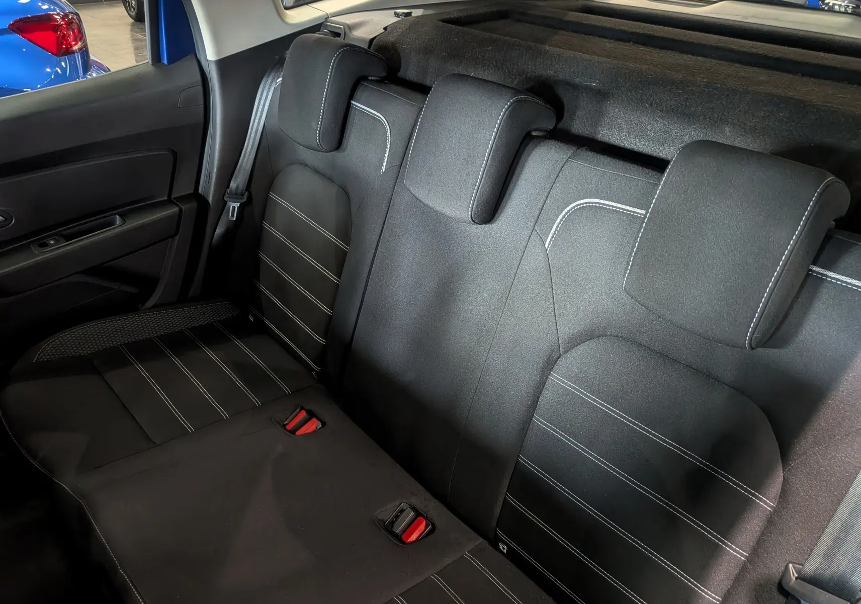 Vue intérieure sur la banquette arrière en tissu noir avec surpiqûres blanches du Dacia Duster Bleu Iron 2022.