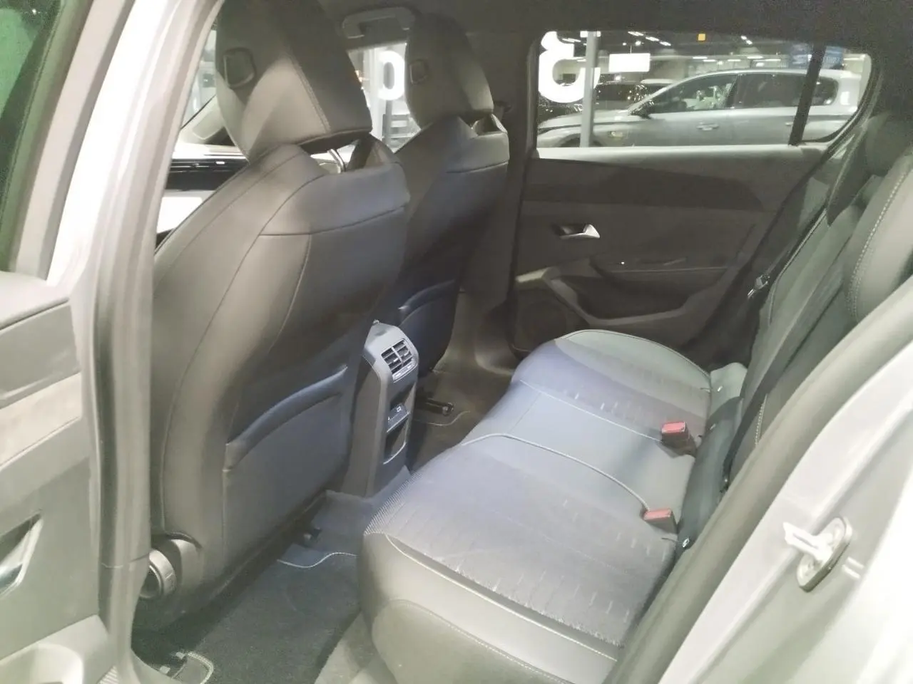 Vue intérieure arrière côté gauche de la Peugeot 308 gris Artense, montrant les sièges et la console centrale avec aérateurs.