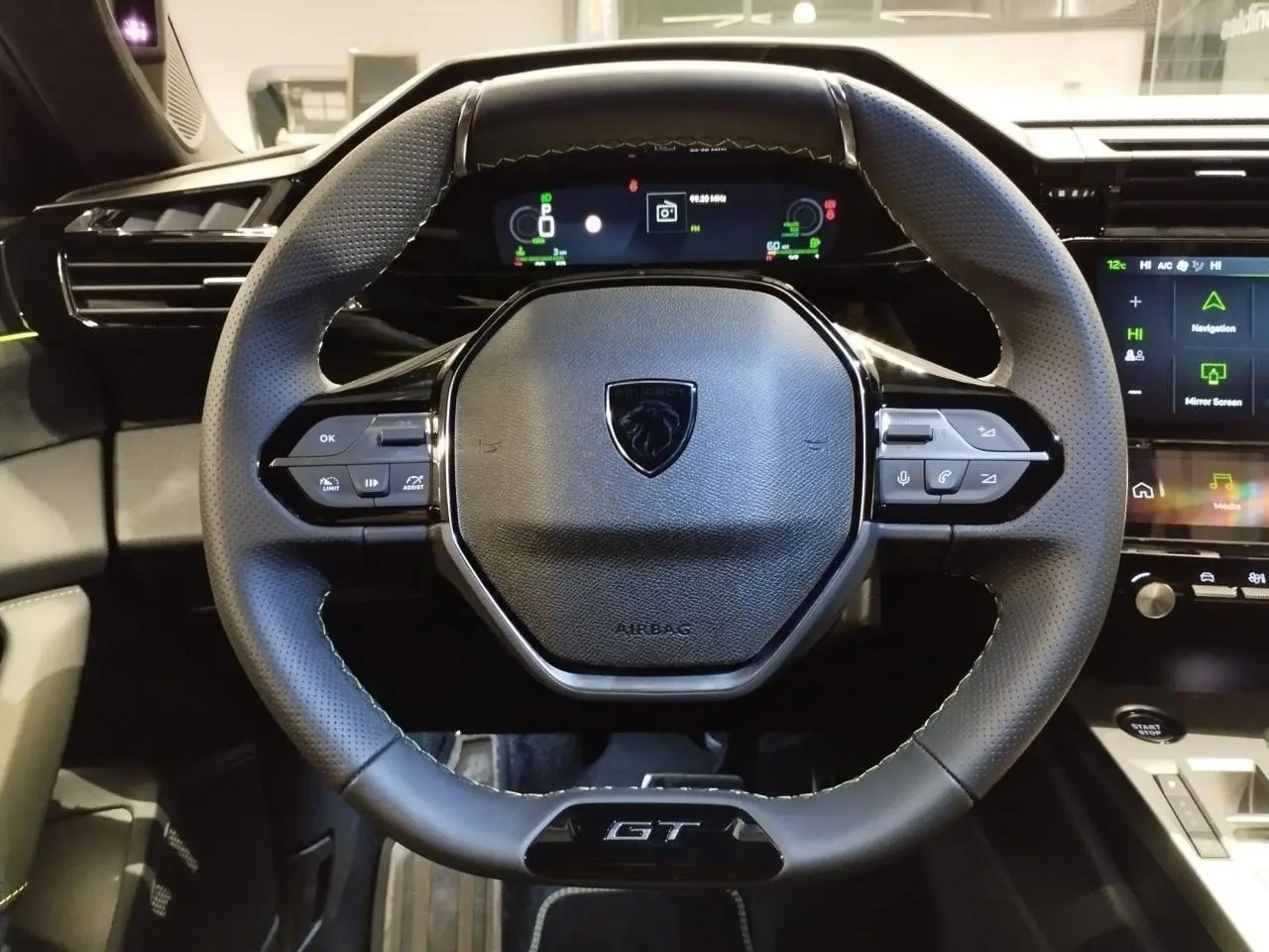 Vue rapprochée du volant compact GT en cuir avec surpiqûres vert Adamite et combiné numérique du Peugeot 308 Hybrid 2026.