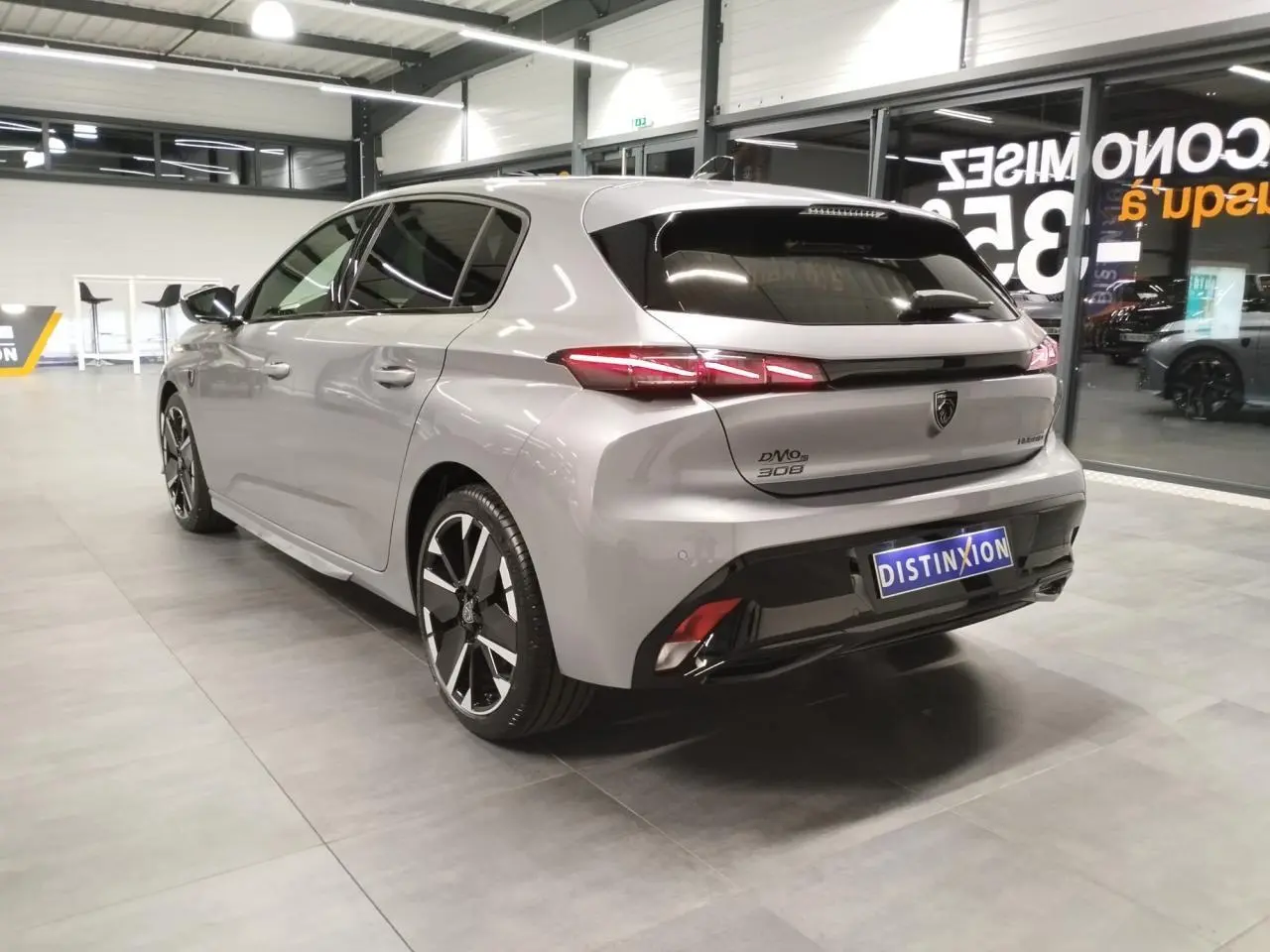 Peugeot 308 gris Artense vue 3/4 arrière droit en intérieur avec jantes alliage bi-tons et feux LED distinctifs.