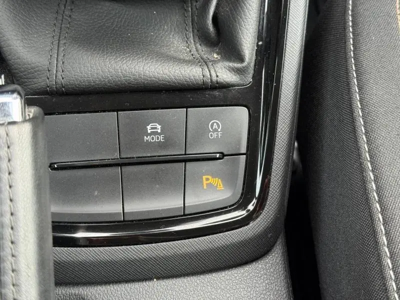 Gros plan sur la console centrale noire du Skoda Kamiq 2024, boutons de mode de conduite et assistance au stationnement visibles.